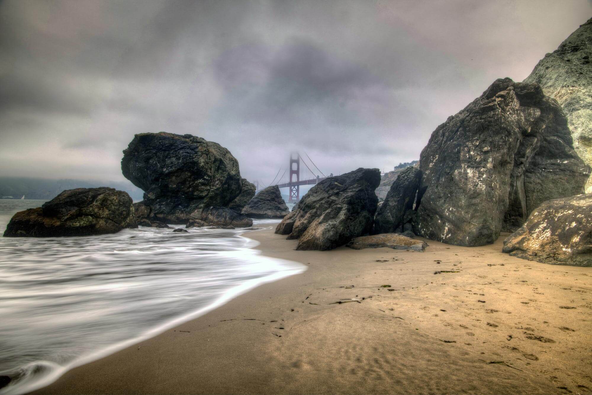 Rocks surrounding Golden Gate Bridge and tide at Marshalls Beach